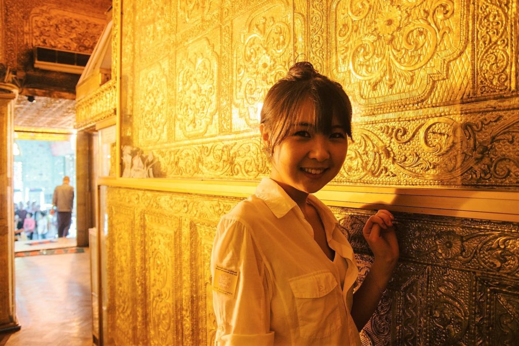 Alice Niu stands in front of golden temple wall.