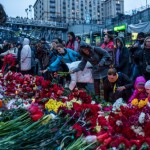 A photograph of people in Kiev laying flowers on the improvised memorial to the victims of shootings on the background of the slogan: "the revolution must go on"