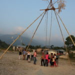 People by a swing and houses in front mountains