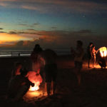 People lighting lanterns on the beach at night