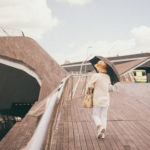Woman in white carrying an umbrella on a bridge