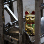 A golden cat statue sits atop a metal object.