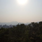 trees in the foreground, mountains and the hazy sky in the background