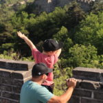 Man lifts boy on ledge of Great Wall of China to see the view.
