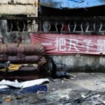 a deteriorating sofa sits outside amidst some garbage