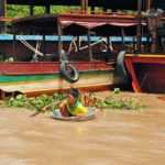 A boy paddling to school in a washing bucket in Chong Kneas Floating Village, Cambodia