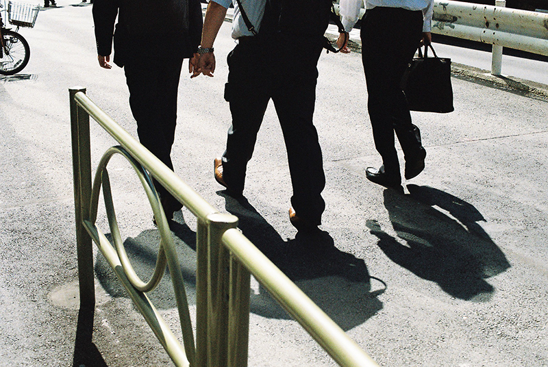 Photo in Andy Takagi’s “Summertime in Tokyo” series; the image shows Salary-men walking in a hot summer day