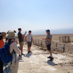 A group of students listen to a professor as they stand at the Dead Sea.