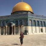 Student stands in front of the famous Temple Mount where the building is bright against a blue sky