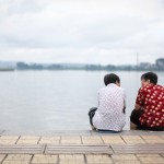 Photo of two women sitting by a lake. Photo by Glen Chua