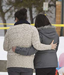Two grieving women console each other at makeshift memorial