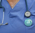 Close up of a doctor wearing strike button on their scrubs