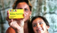 A woman holds a child and a Bolsa Familia card