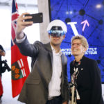 Kathleen Wynne, premier of Ontario, right, poses for a selfie photograph with a man wearing a virtual reality helmet.
