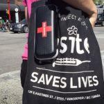 A woman carries a naloxone kit and a bag from Insite, the safe injection site