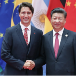 Justin Trudeau and Xi Jinping shake hands in front of a row of international flags