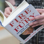 A person stands reading Michael Wolff's book Fire and Fury.
