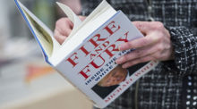 A person stands reading Michael Wolff's book Fire and Fury.