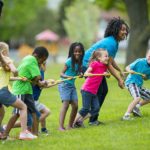 Kids and counselors playing tug of war at summer camp.