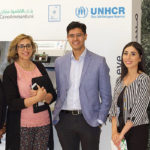A group of student researchers pose in front of a UNHCR ATM.