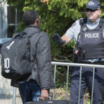 An asylum-seeker is confronted by an RCMP officer as he enters Canada from the United States
