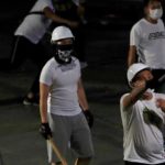 Men in white T-shirts with poles are seen in Yuen Long after attacked anti-extradition bill demonstrators at a train station, in Hong Kong, China