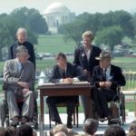 President George H.W. Bush signs the Americans with Disabilities Act during a ceremony on the South Lawn of the White House on July 26, 1990.