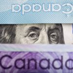 An American $100 bill peeks through a few Canadian bills