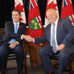 Andrew Scheer and Doug Ford sit side by side, shaking hands
