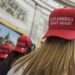 A young woman wears a backwards "Make America Great Again" hat