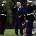 Joe Biden greets military personnel with a salute as he steps off of Air Force One