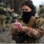 Ukrainian army soldier checks her phone after a military sweep on the outskirts of Kyiv