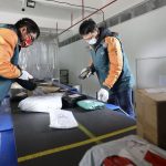 Two postal workers scanning packages at Chinese mail facility
