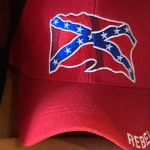 Red baseball cap bearing the confederate flag and the word "rebel" on the bill