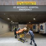 Paramedics pushing a patient on a stretcher infront of St. Michael's Hospital's Emergency Entrance in Toronto, ON