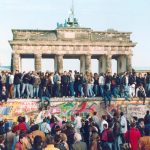 Berlin Wall, people on top with the Brandenburg Gates in the background